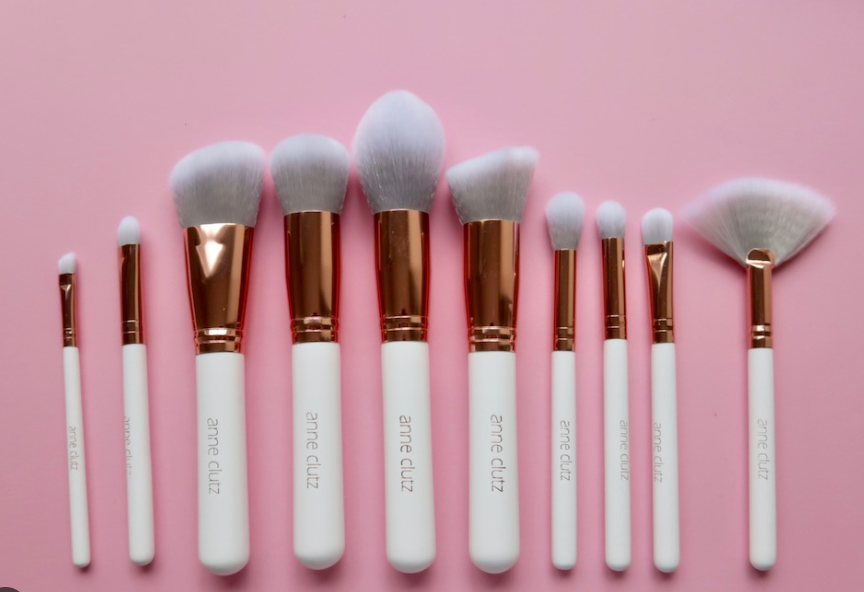 Anne Clutz Brushes 10 piece set white handles rose gold ferrules pink background
